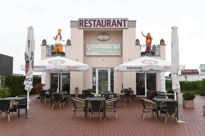 Un restaurante llamado Grenzenlos con terraza y dos estatuas en el balcón.