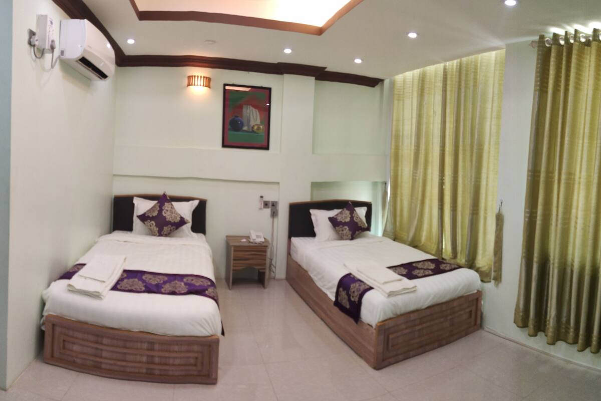A hotel room with two beds, a nightstand, a telephone, and a painting on the wall.