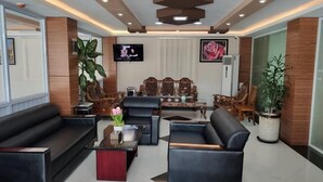 A modern lobby with leather sofas, a coffee table, and a TV mounted on the wall. - Motel Minbu (Minbu)