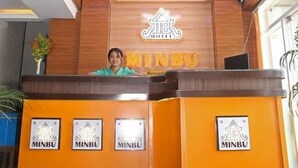 A reception desk with a wooden finish, a chandelier, clocks, and a large window. - Motel Minbu (Minbu)