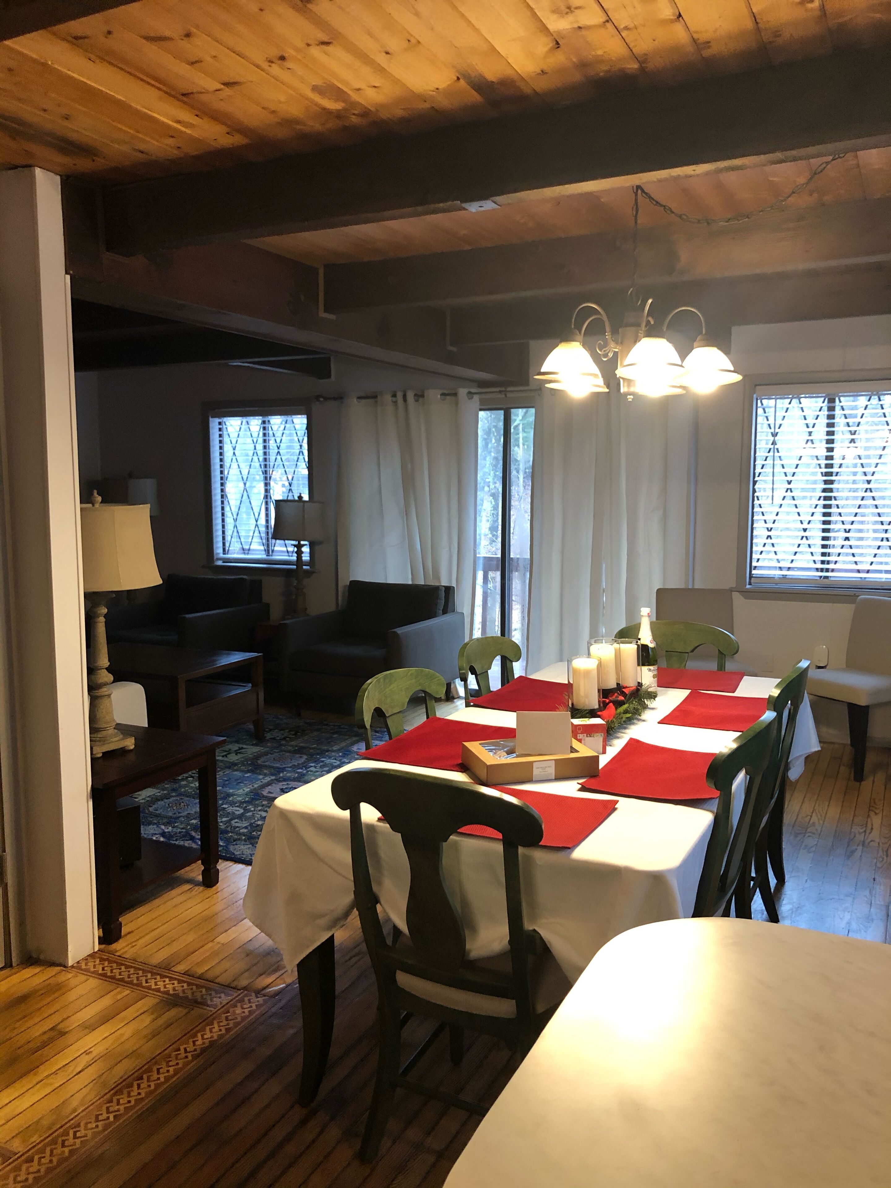 Un comedor con una mesa de madera dispuesta para cuatro personas, rodeada de sillas, y una araña colgante.