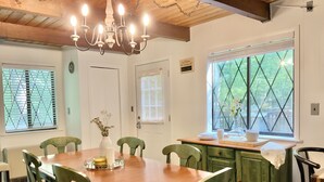 A dining area with a wooden table, green chairs, a chandelier, and a window with a view of trees. - Facilities all year round (Bushkill)