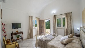 A bedroom with a bed, a chair, a TV, a window, and a view of the outdoors. - Il Mandorlo (Tramonti)