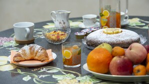 A table with a croissant, a fruit plate, a pitcher, a glass of juice, and a teapot. - Il Mandorlo (Tramonti)
