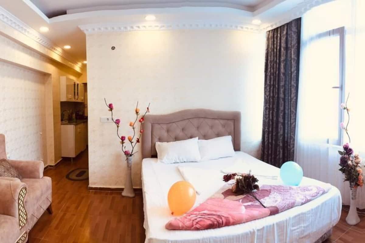 A hotel room with a bed, a sofa, a chair, and a small table.