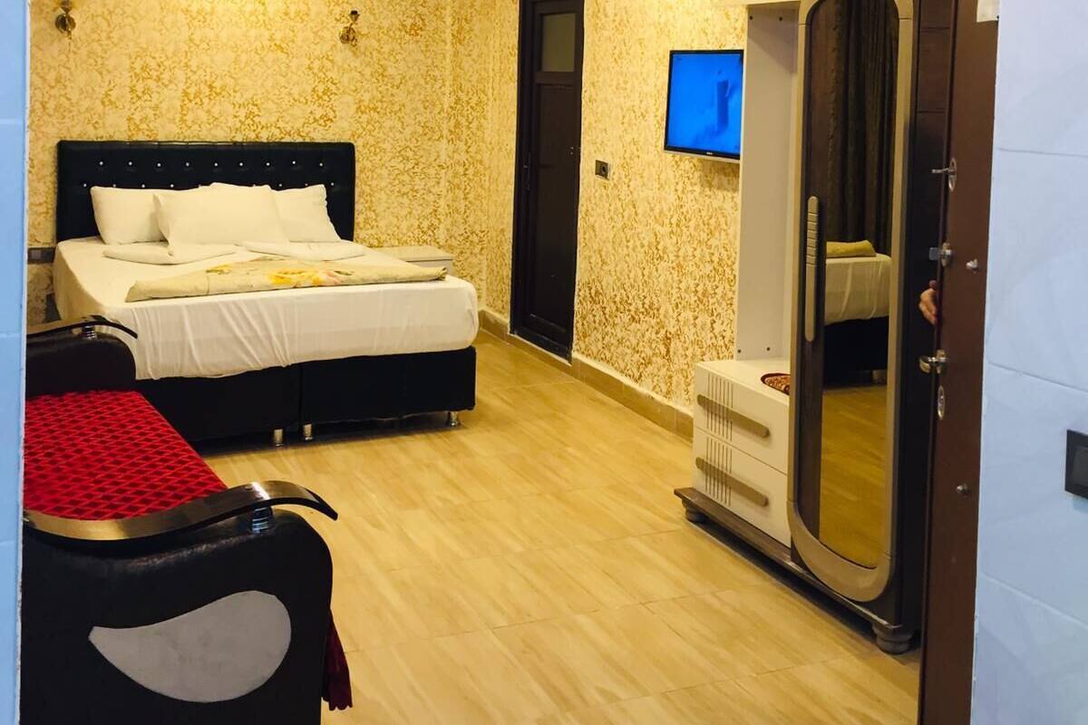 A hotel room with a bed, a TV, a wardrobe, and a mirror.