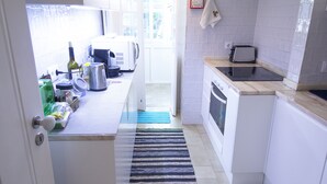 Eine Küche mit weißen Schränken, einer Mikrowelle, einem Toaster und einem Wasserkocher auf der Arbeitsfläche.