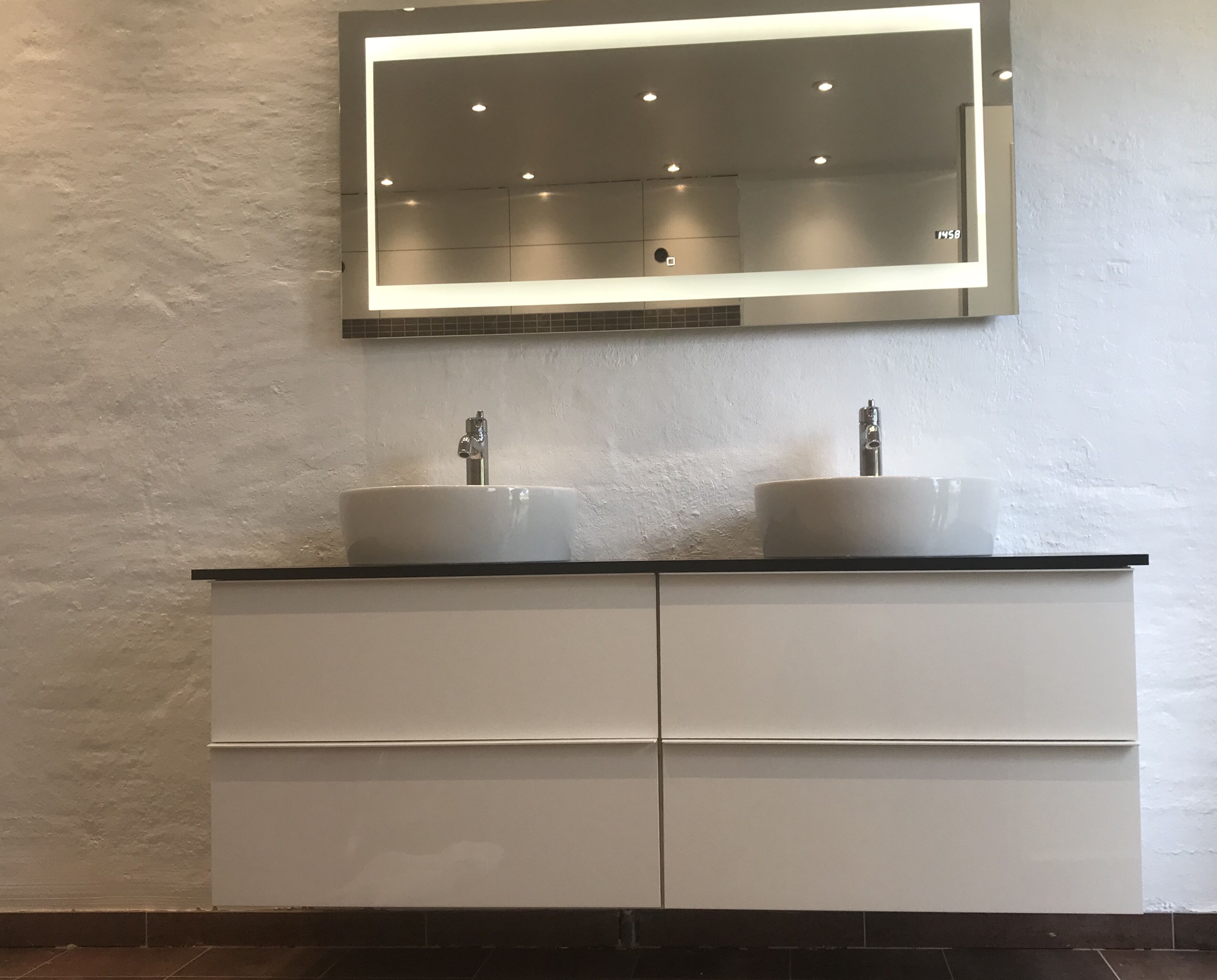 Une salle de bain avec deux lavabos, un grand miroir et un meuble sous le plan de travail.