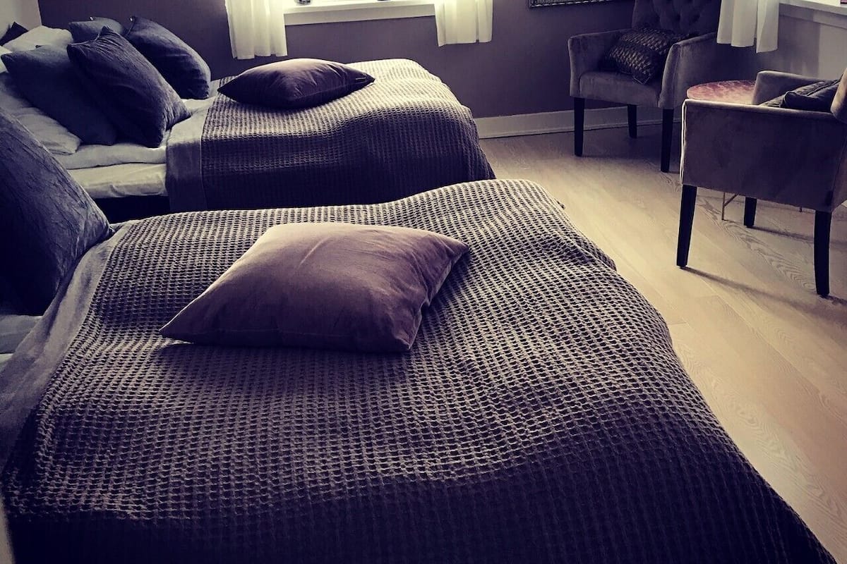 A modern bedroom with two large beds, a chair, and a small table.