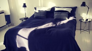 A bedroom with a large bed, two bedside tables, and a radiator. - Katrinelund Bed and Breakfast (Tikob)