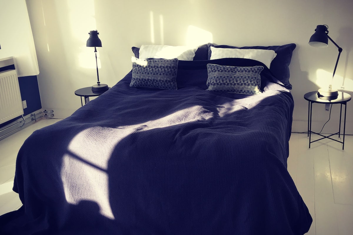 A bedroom with a large bed, two bedside tables, and a radiator.