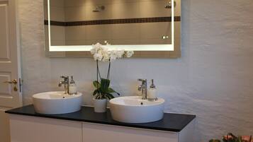 Baño con dos lavamanos, un espejo y una orquídea en maceta.