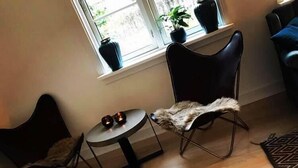 A room with a round table, two chairs, a black furry rug, and a window with potted plants. - Katrinelund Bed and Breakfast (Tikob)