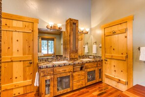 Un baño de madera con un espejo grande, dos lavamanos y un perchero para toallas.