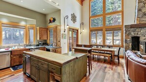 A spacious kitchen with a large island, wooden cabinets, and a stone fireplace.