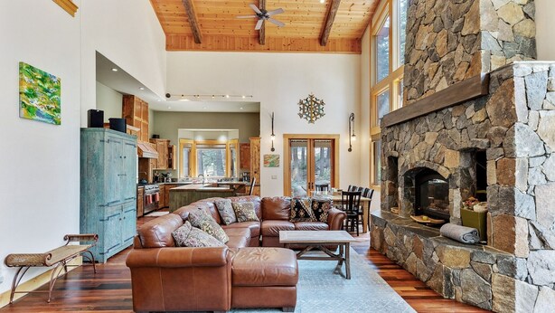 A spacious living room with a stone fireplace, leather sectional sofa, and a dining area.