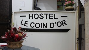 A sign for 'Hostel Le Coin d'Or' with a decorative flower arrangement in front. - Hostel Le Coin D or (Algiers)