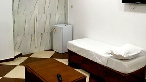 A small, clean room with a bed, a refrigerator, a TV, and a remote control on a table. - Hostel Le Coin D or (Algiers)