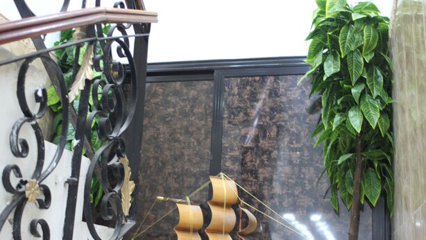 A staircase with ornate black metal railings and a ship model in the background. - Hostel Le Coin D or (Algiers)