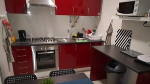 A compact kitchen with red cabinets, a gas stove, a microwave, and a sink.