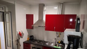 A compact kitchen with red cabinets, a gas stove, a built-in oven, a sink, and a coffee maker.