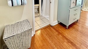 Ein Badezimmer mit Duschvorhang, Holzboden, Spiegel und einer Wandablage mit Handtüchern.