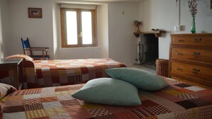 A bedroom with two beds, a dresser, a chair, and a window.