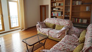 A living room with a sofa, a coffee table, and a bookshelf filled with books.