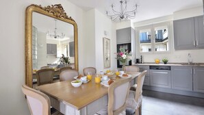 A dining area with a wooden table, chairs, and a large mirror. There is a chandelier above the table. - Incredibly Luxurious Bright 2 Bed with Balcony and Wow Eiffel View (Paris)