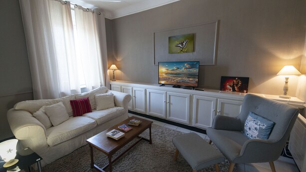 Uma sala de estar com sofá, poltrona, mesa de centro e televisão em um móvel.