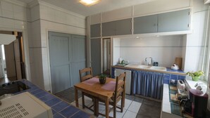 Uma cozinha com mesa de jantar, cadeiras, fogão e pia.