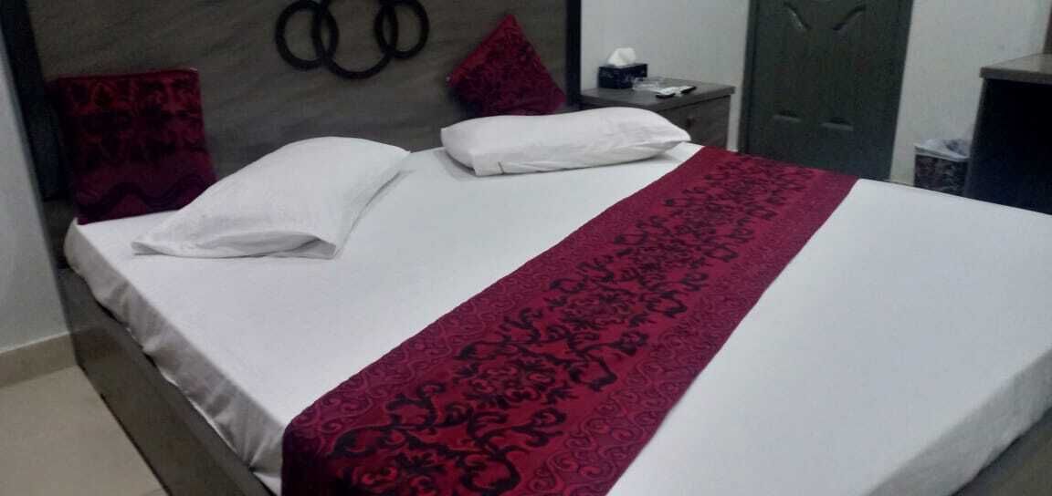 Un lit bien fait, avec des draps blancs et une couvre-lit rouge à motifs.