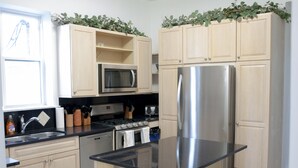 Une cuisine moderne avec des meubles en bois clair, des appareils en acier inoxydable et un îlot central doté de tabourets de bar.