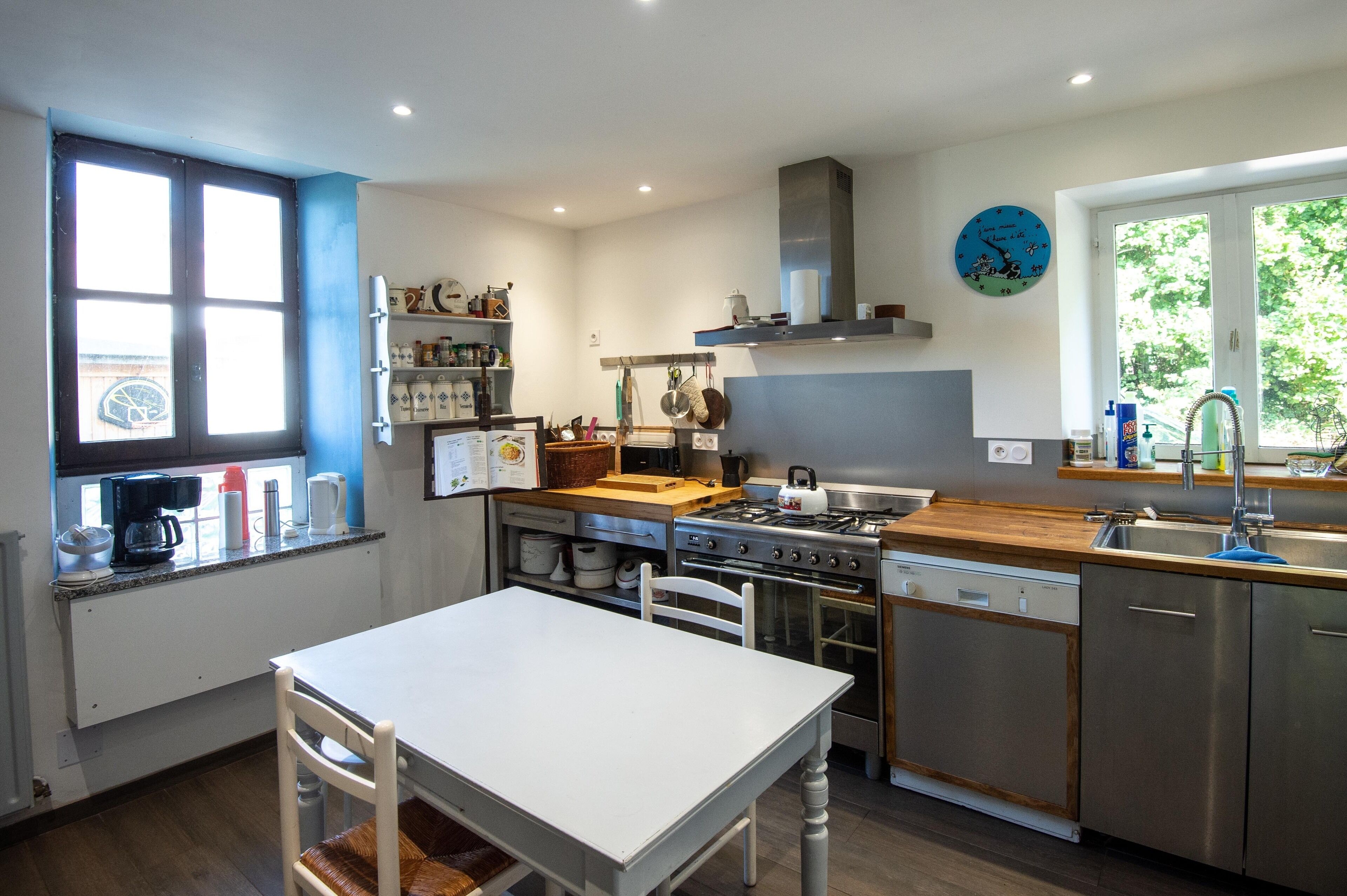 A modern kitchen with a white table, stainless steel appliances, and a window with a view.