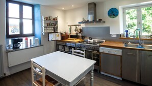 Une cuisine moderne avec une table blanche, des appareils en acier inoxydable et une fenêtre donnant sur un beau paysage.