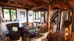 Un salon confortable avec un canapé, des fauteuils, une table basse et un escalier menant à l’étage.