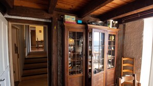Un escalier en bois mène à une salle à manger où se trouve un buffet contenant de la vaisselle et des verres.
