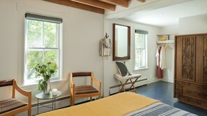 A bedroom with a bed, two chairs, a table with a candle, a mirror, and a wardrobe.