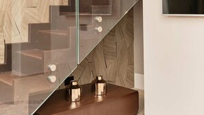A modern staircase with glass railings and a wooden geometric wall design. - Palazzo Salomone (Syracuse)