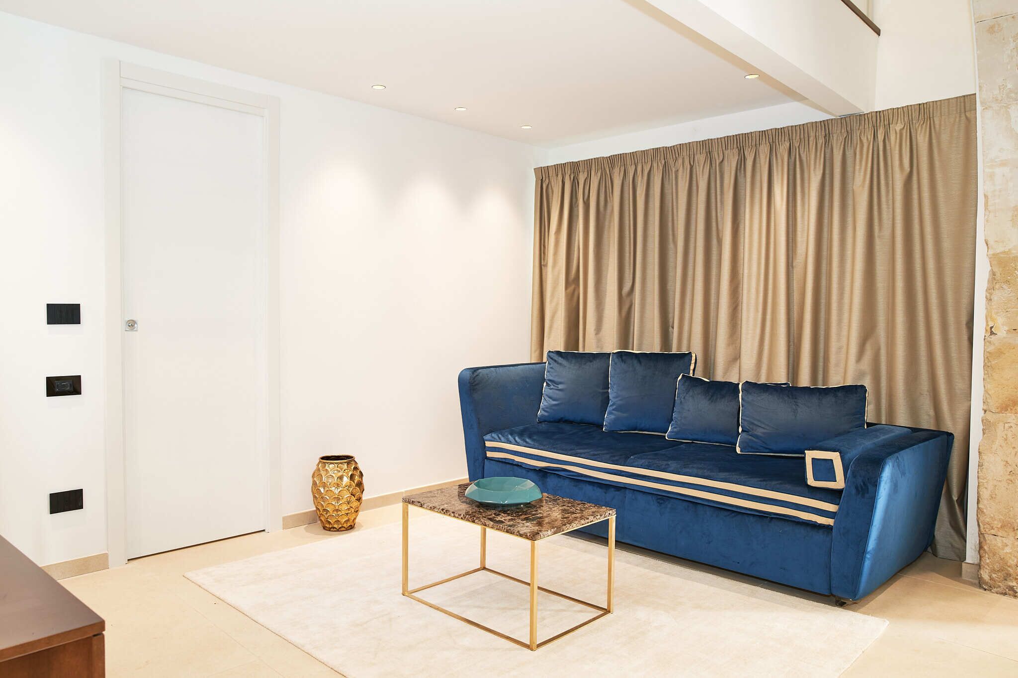 Un salon moderne avec un canapé bleu, une petite table basse et un rideau beige.