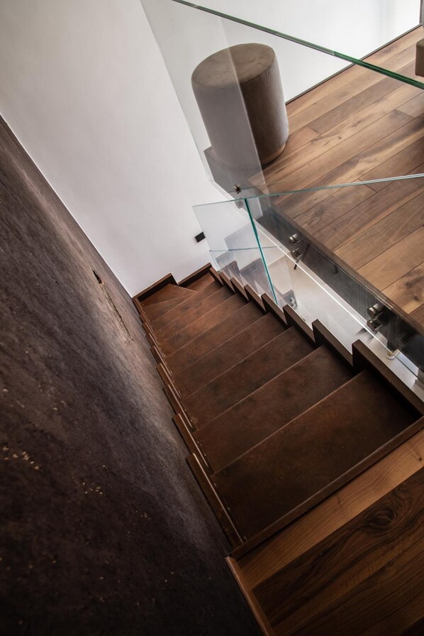 Una escalera moderna con barandillas de cristal y peldaños de madera.