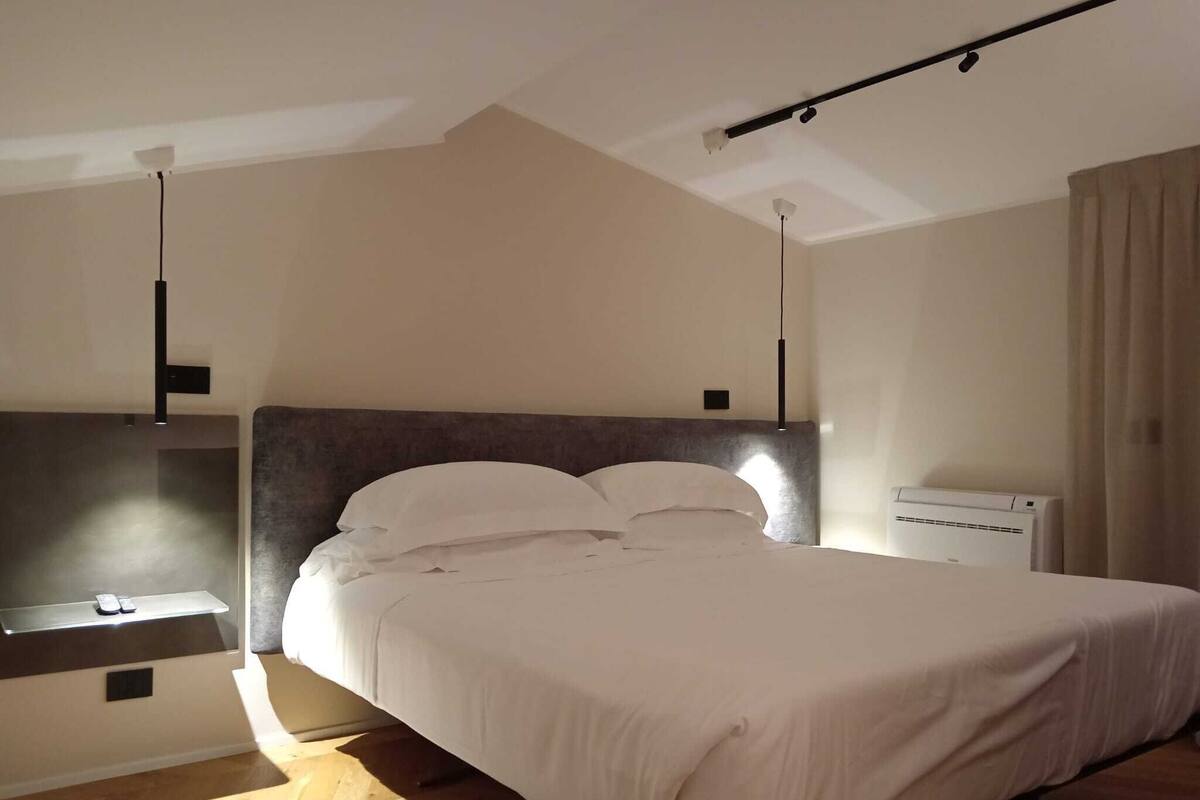A bedroom with a bed, bedside table, and an air conditioning unit.