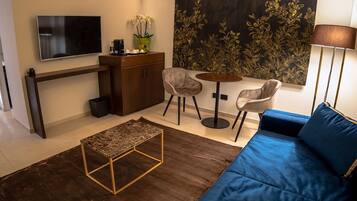 Een moderne woonkamer met een blauwe bank, een bijzettafeltje, een televisie, een kast en een schilderij aan de muur.
