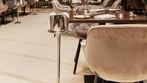 A modern restaurant interior with high ceilings, hanging pendant lights, and a bar area with wine bottles. - Palazzo Salomone (Syracuse)