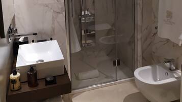 A modern bathroom with a glass-enclosed shower, a white sink, and a bidet.