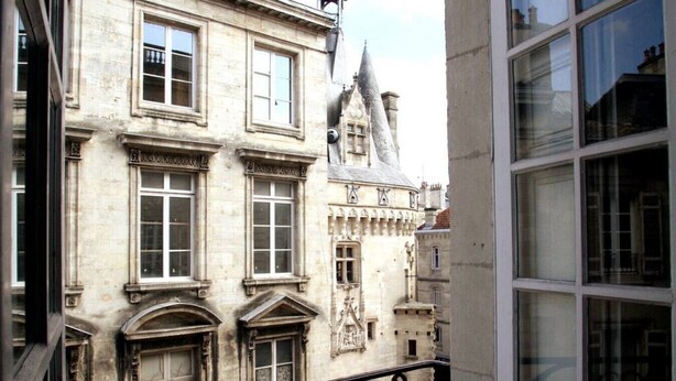 Un edificio histórico con detalles arquitectónicos ornamentales, incluyendo una torre y múltiples ventanas.