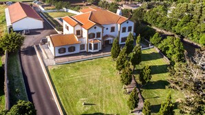 An aerial view of a large, white building with a red-tiled roof, surrounded by green lawns and trees. - Casa Marques (Angra do Heroismo)