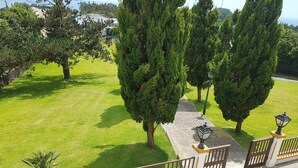 A well-maintained grassy area with a paved walkway, bordered by a metal fence with decorative posts. - Casa Marques (Angra do Heroismo)