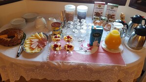A breakfast buffet table with various food items, including a cake, fruit, and beverages. - Casa Marques (Angra do Heroismo)