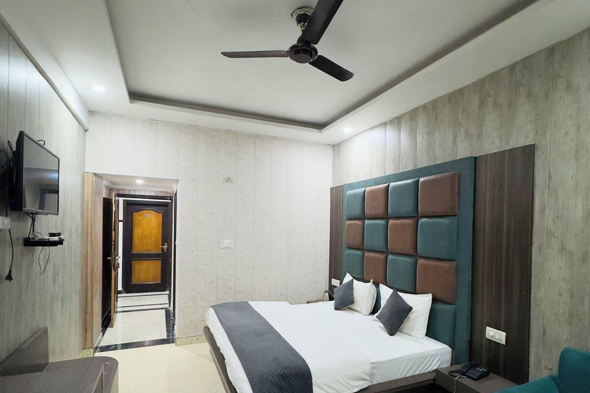 Una habitación de hotel moderna con una cama grande, un escritorio, una silla, un televisor y un ventilador de techo.